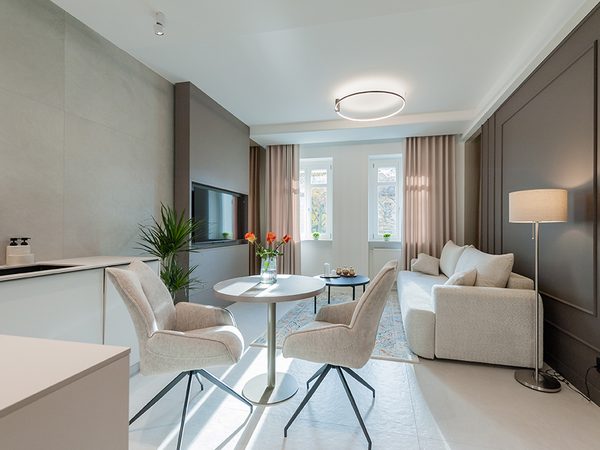 Jasny salon z okrągłym stołem, fotelami i sofą